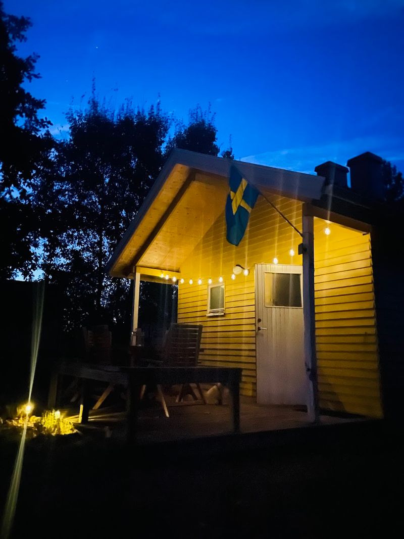 Stuga Eos lit up with string lights on a summer evening